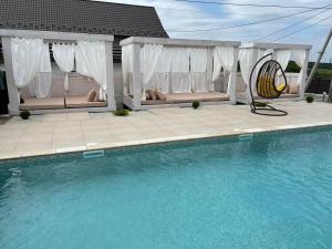 - une piscine avec bancs et une maison dans l'établissement Café Chalet Edelweiss Holiday Home, à Zbarazh