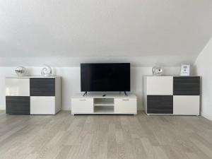 a living room with a flat screen tv and two white cabinets at Bella Casa in Überlingen
