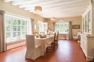 - une salle à manger avec une table, des chaises et des fenêtres dans l'établissement Manderley, à Arceau