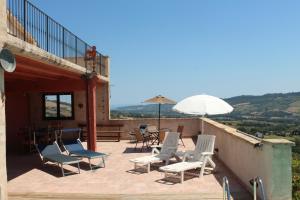 a deck with chairs and a table and an umbrella at Il Piccolo Carro Apartments in Monterubbiano