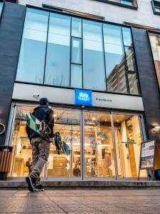 a man carrying a skateboard in front of a store at ibis budget Santiago Providencia in Santiago