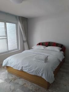 1 dormitorio con 1 cama blanca grande y ventana en Cha-am Beach Vacation Home en Cha Am