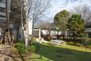 a yard with white chairs and a table at Dullstroom Inn in Dullstroom