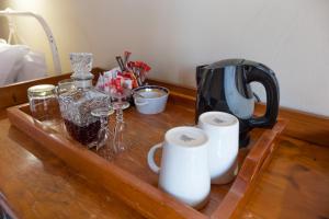 Dullstroom Inn في دولستروم: طاولة خشبية مع وعاء القهوة وأكواب عليها