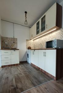 a kitchen with white cabinets and a washer and dryer at Panna Cottage in Badacsonytomaj