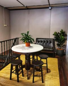 a table with four chairs and a table with a plant on it at Treehouse Hostel in Kuching
