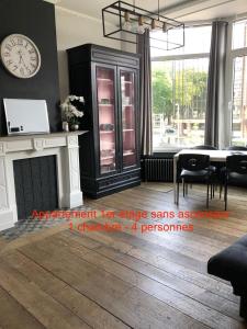 a living room with a clock on the wall and a fireplace at La Bourgeoise in Liège