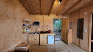 ニエブラにあるCABAÑAS ALTO BELLAVISTA NIEBLAの木製の壁のキッチン、冷蔵庫が備わります。