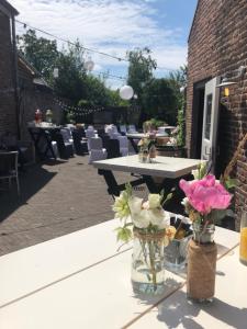 a patio with tables and chairs and flowers in vases at Het Heerenlogement Beusichem in Beusichem