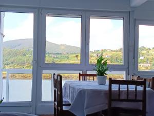 uma sala de jantar com uma mesa e vistas para a água em Apartamento Ría Navia em Navia