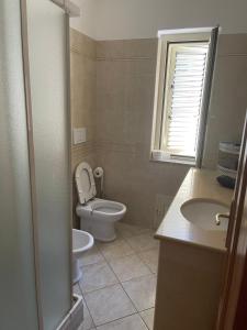 a bathroom with a toilet and a sink and a window at Confortevole e Luminoso Appartamento 100mq a Falerna con Vista sul Paese e sul Promontorio con Free WiFi Free Parking e Smart TV in Falerna