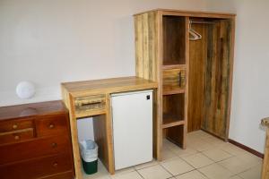 a kitchen with a small refrigerator and wooden cabinets at Holiday Hotel in San Pedro