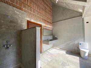 uma casa de banho com um WC e uma parede de tijolos em Ostel In em Pondicherry