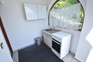 uma pequena cozinha com um lavatório e uma janela em Apartments Biga em Donji Morinj