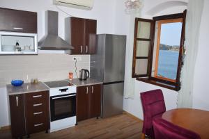 a kitchen with a refrigerator and a table and a window at Apartman Plava riba in Šibenik