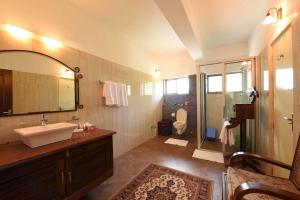a bathroom with a sink and a toilet and a mirror at Sourenee Tea Estate in Mirik +49 photos