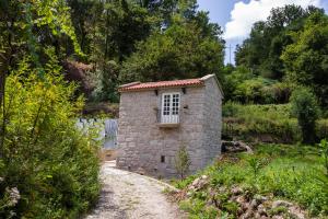 a small brick building with a window on a dirt road at COUNTRY HOUSE by the RIVER - NATIONAL PARK in Arcos de Valdevez