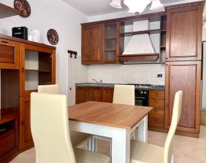 a kitchen with a wooden table and white chairs at Sunset Boutique Apartment in Marina di Massa