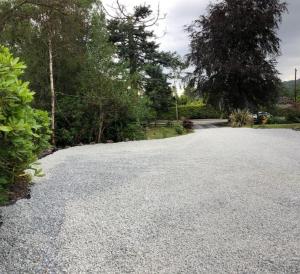 a driveway with gravel and trees in a yard at Cedar Lodge in Oban