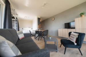een woonkamer met een bank, stoelen en een tafel bij Angel by the Waves in Oostende