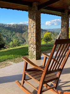 een houten stoel op een veranda met uitzicht bij Pousada das Pedras in Monte Verde
