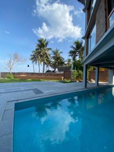una piscina frente a una casa con palmeras en Ostel In en Pondicherry