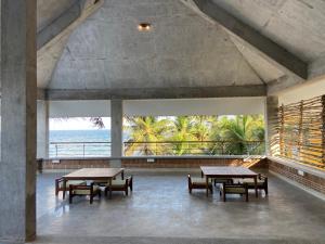 uma sala com mesas e bancos e vista para o oceano em Ostel In em Pondicherry