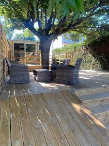a wooden deck with two chairs and a tree at Les Cygnes au bord du loing in Montigny-sur-Loing