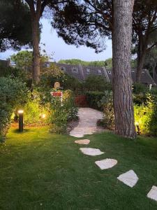 einen Garten mit einem Baum und Steppsteine im Gras in der Unterkunft Emerald Cottage Calaverde Santa Margherita di Pula in Fort Village