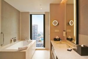 莎阿南Doubletree By Hilton Shah Alam I-City的带大浴缸和大窗户的浴室