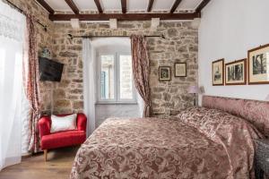 um quarto com uma cama e uma cadeira vermelha em Apartments Kaleta em Split