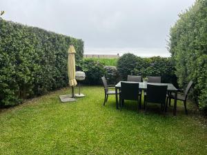 une table, des chaises et un parasol dans l'herbe dans l'établissement Vila Chã Beach House by Trip2Portugal, à Vila Chã