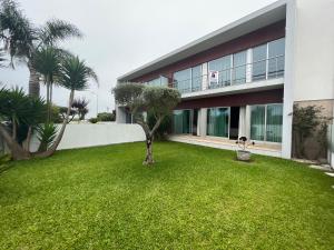 a house with a green yard with a palm tree at Vila Chã Beach House by Trip2Portugal in Vila Chã