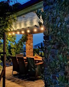 een houten tafel en stoelen onder een pergola met verlichting bij Apartmani Tonkica in Supetarska Draga