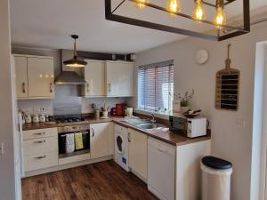 a kitchen with white cabinets and a sink at Norwich, Lavender House, 3 Bedroom House, Private Parking and Garden in Norwich