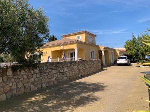 una casa gialla con un muro di pietra e una recinzione di Villa proche cap d’agde a Bessan