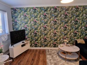 a living room with a wall with a tropical wallpaper at Norwich, Lavender House, 3 Bedroom House, Private Parking and Garden in Norwich