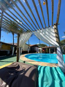 uma grande piscina azul com uma pérgula branca em Pousada Hippopotamus Jeri em Jericoacoara