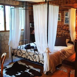 a bedroom with a canopy bed with white curtains at Chambre d'hôtes le petit Ranch in Los Masos