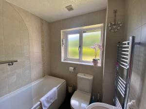 Un baño con bañera, inodoro y ventana. en Buena Vista, en Tintagel 25 fotos más