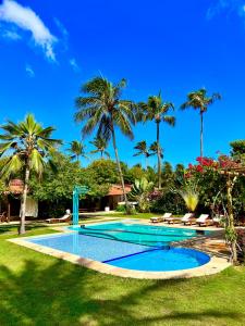 una piscina en un patio con palmeras en Tucano Pousada, en Cumbuco