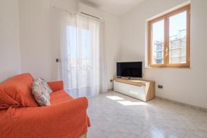 a living room with a orange couch and a television at Casa Olimpia in Santa Teresa di Riva