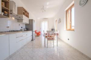 a kitchen with white cabinets and a table and chairs at Casa Olimpia in Santa Teresa di Riva