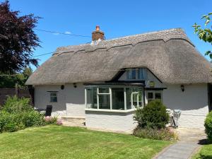 a thatch roofed house with a grass yard at Thatch Cottage, East Boldre nr Beaulieu and Lymington in Brockenhurst