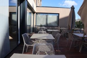 a patio with tables and chairs on a balcony at Meu Hotel Porto Gandra in Paredes