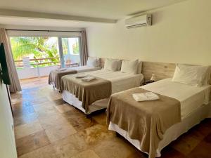 a hotel room with two beds and a balcony at Tucano Pousada in Cumbuco