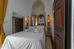 a bedroom with a white bed with two pillows on it at Riad Safar in Marrakesh