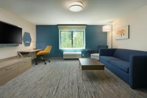 Holiday Inn Express & Suites - Williamstown - Glassboro, an IHG Hotel في ويليامزتاون: غرفة معيشة مع أريكة زرقاء ومكتب