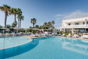 una piscina in un resort con sedie e palme di Canne Bianche Lifestyle Hotel a Torre Canne