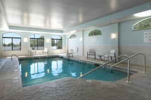 a large swimming pool in a building with tables and chairs at Holiday Inn Express & Suites - Williamstown - Glassboro, an IHG Hotel in Williamstown